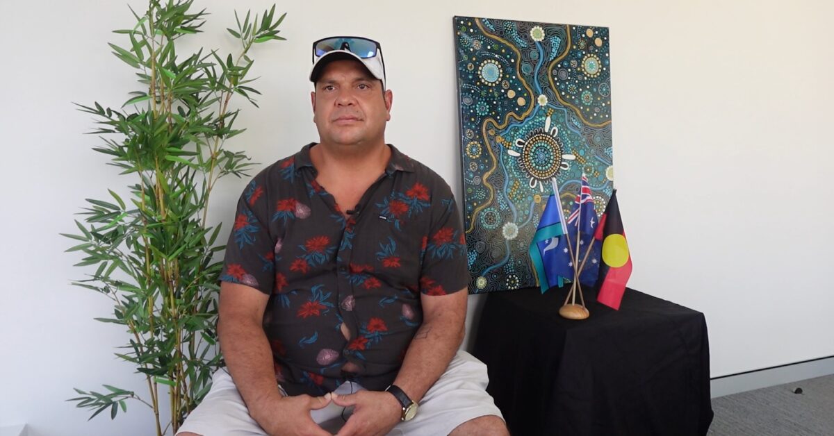 Man seated in front of Indigenous artwork