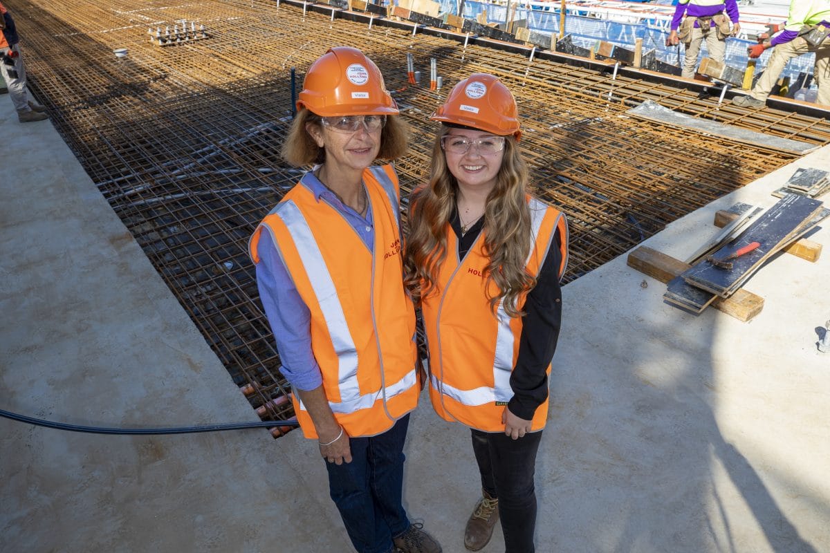 Two women in hard hats and high-visibility vests on a construction site